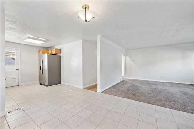 spare room featuring light carpet and a textured ceiling