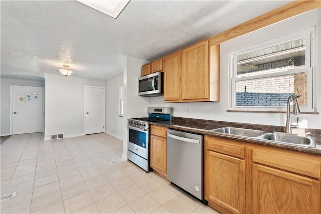 kitchen featuring light tile patterned floors, sink, a textured ceiling, and appliances with stainless steel finishes