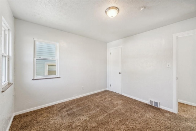 carpeted spare room with a textured ceiling