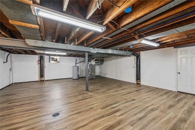 basement with heating unit, water heater, and wood-type flooring