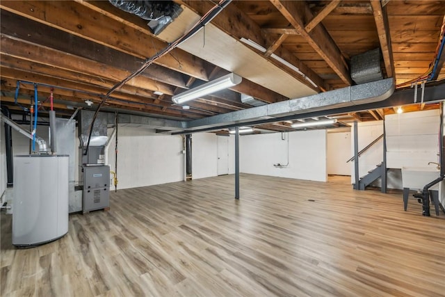 basement featuring heating unit, hardwood / wood-style flooring, and gas water heater