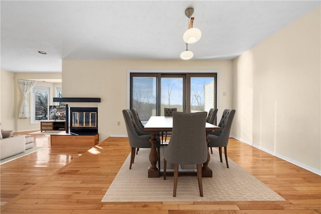 dining area with light hardwood / wood-style floors and a multi sided fireplace