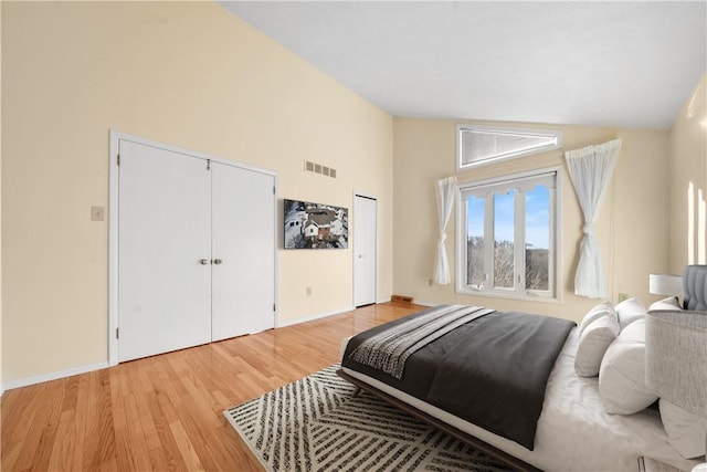 bedroom featuring lofted ceiling, light wood-type flooring, and a closet