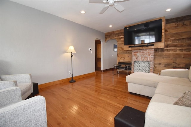 living room with wood walls, hardwood / wood-style flooring, and ceiling fan