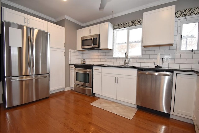 kitchen featuring appliances with stainless steel finishes, white cabinetry, sink, dark hardwood / wood-style flooring, and backsplash