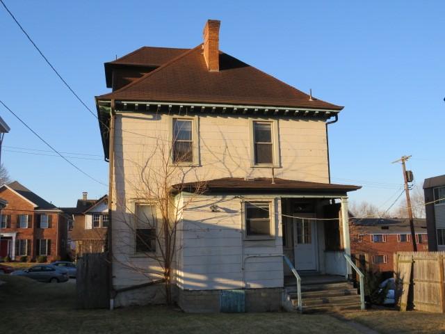 rear view of property with a chimney and fence