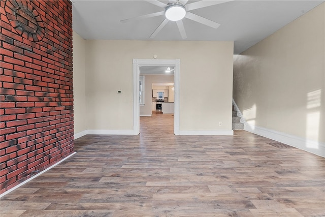 empty room featuring brick wall and wood-type flooring