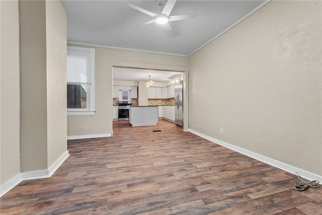 unfurnished living room with ornamental molding, ceiling fan with notable chandelier, and hardwood / wood-style floors