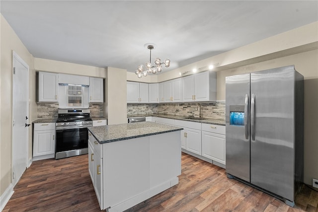 kitchen with white cabinetry, a kitchen island, decorative light fixtures, dark hardwood / wood-style flooring, and stainless steel appliances