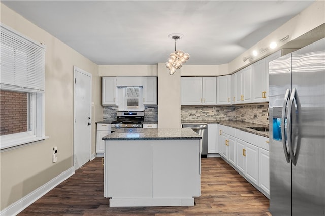 kitchen with decorative light fixtures, white cabinetry, stainless steel appliances, and a kitchen island