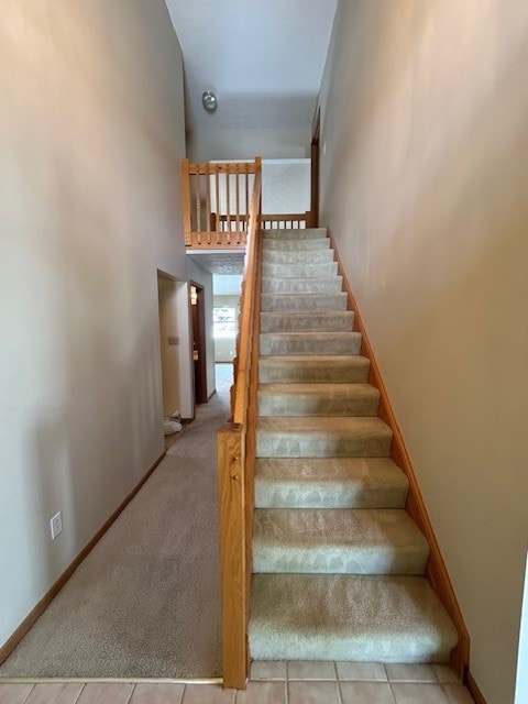 staircase with a towering ceiling and carpet floors