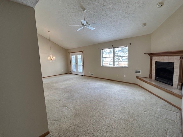 unfurnished living room with a fireplace, a textured ceiling, ceiling fan, and vaulted ceiling