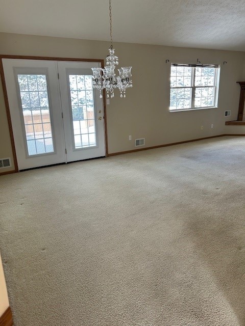 empty room with plenty of natural light, carpet, and a notable chandelier