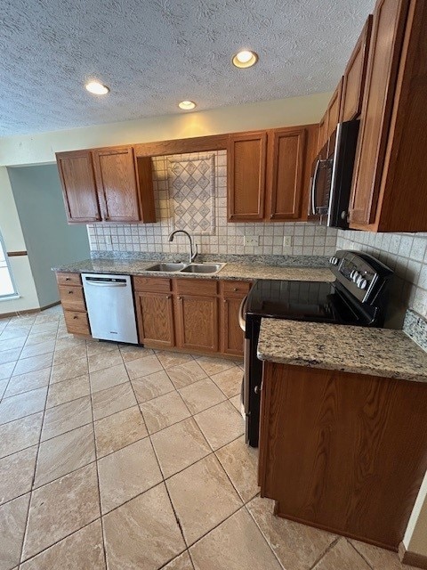 kitchen with light stone countertops, a textured ceiling, appliances with stainless steel finishes, tasteful backsplash, and sink