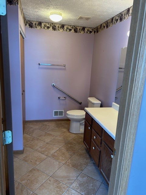 bathroom with a textured ceiling, toilet, and vanity