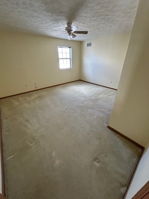 carpeted empty room featuring ceiling fan and a textured ceiling