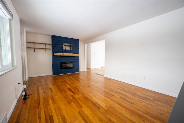 unfurnished living room featuring wood-type flooring and a large fireplace