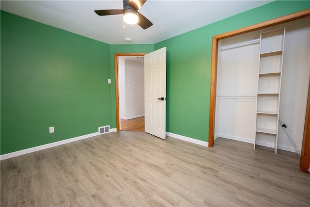 unfurnished bedroom with light wood-type flooring, ceiling fan, and a closet