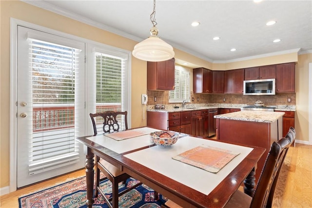 dining space featuring crown molding and light wood-type flooring