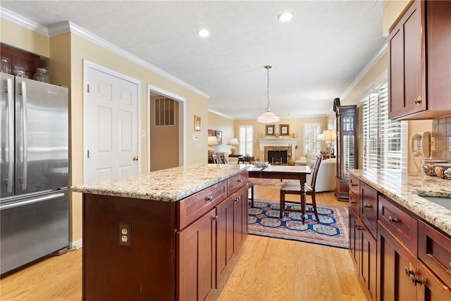 kitchen with ornamental molding, a center island, a wealth of natural light, and stainless steel refrigerator