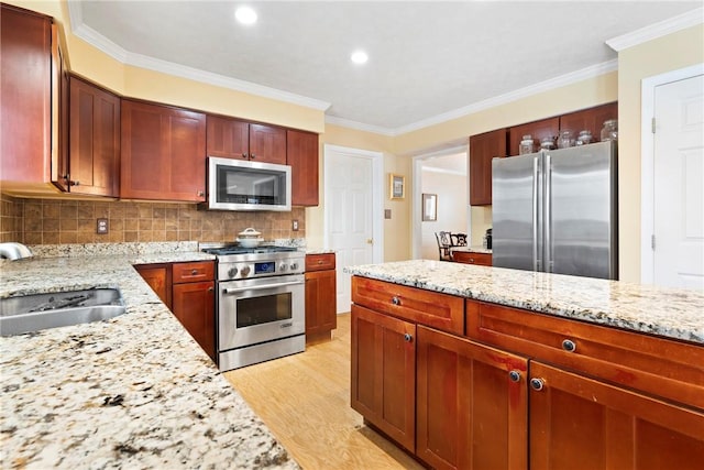 kitchen with light stone countertops, sink, appliances with stainless steel finishes, and crown molding