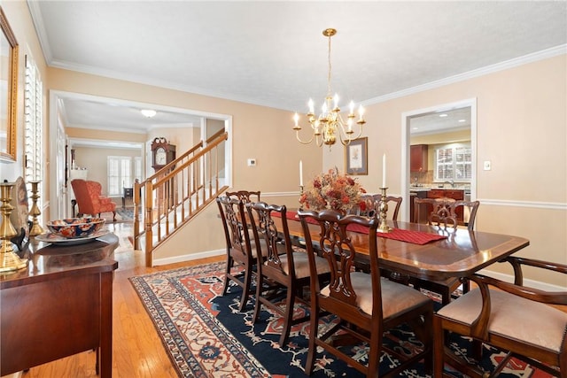 dining area with crown molding, light hardwood / wood-style floors, and a chandelier