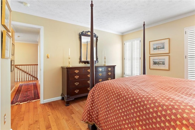 bedroom with light wood-type flooring, ornamental molding, and a textured ceiling