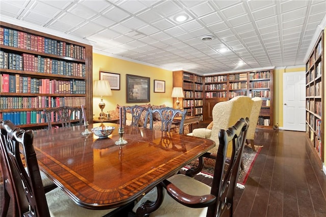 dining room featuring crown molding, built in features, and dark hardwood / wood-style floors