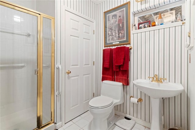 bathroom with sink, a shower with door, toilet, and tile patterned flooring