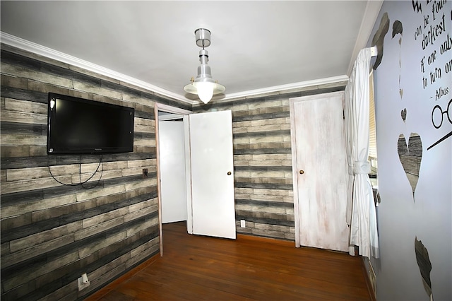 interior space featuring ornamental molding, dark wood-type flooring, and wooden walls