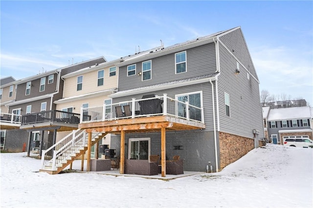 snow covered house featuring a wooden deck