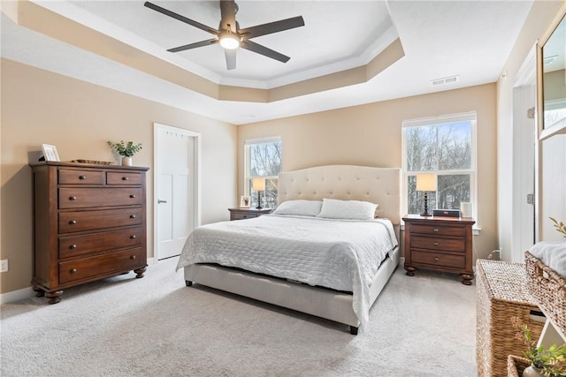 bedroom featuring ceiling fan, light colored carpet, a tray ceiling, and ornamental molding