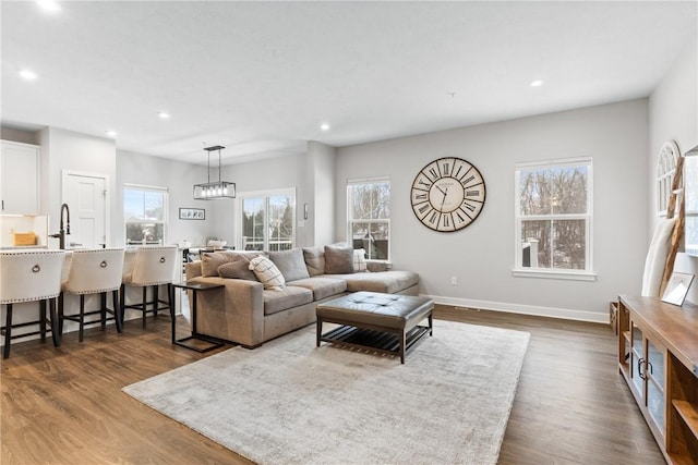 living room with sink, a chandelier, and dark hardwood / wood-style flooring