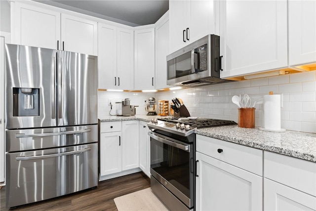 kitchen featuring light stone countertops, white cabinetry, appliances with stainless steel finishes, and tasteful backsplash