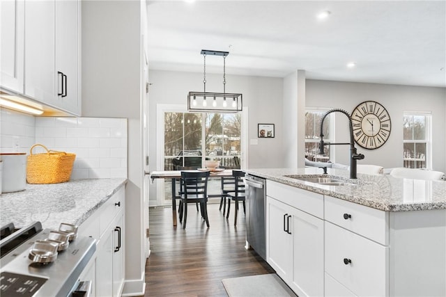 kitchen with stainless steel dishwasher, hanging light fixtures, sink, white cabinetry, and decorative backsplash