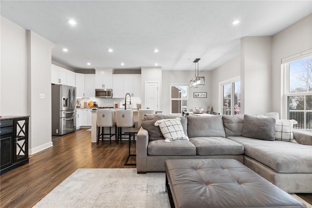 living room featuring sink, a notable chandelier, and dark hardwood / wood-style flooring