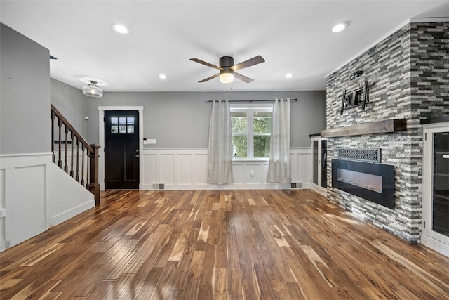 unfurnished living room featuring hardwood / wood-style flooring, a stone fireplace, and ceiling fan