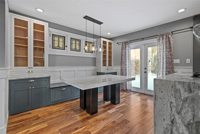 kitchen featuring hardwood / wood-style floors, light stone counters, pendant lighting, and french doors