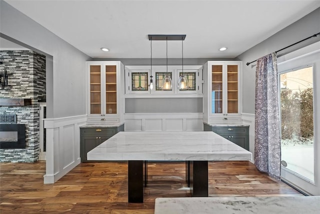 dining room with a stone fireplace and dark hardwood / wood-style flooring