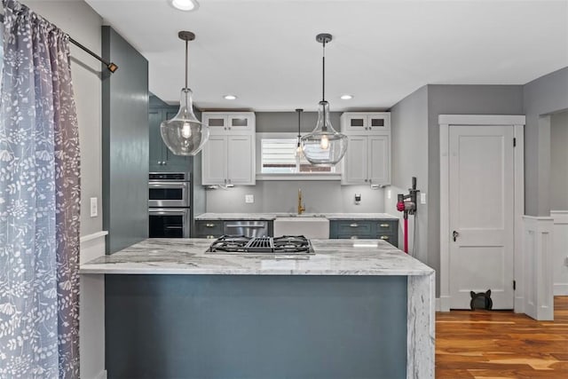 kitchen with light stone counters, white cabinetry, appliances with stainless steel finishes, and hanging light fixtures