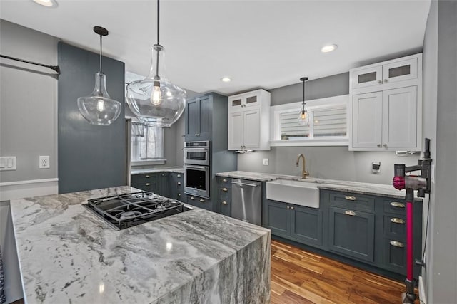 kitchen featuring appliances with stainless steel finishes, sink, decorative light fixtures, white cabinets, and hardwood / wood-style flooring