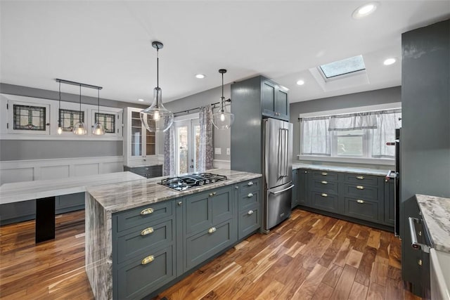 kitchen featuring light stone countertops, kitchen peninsula, appliances with stainless steel finishes, and a skylight