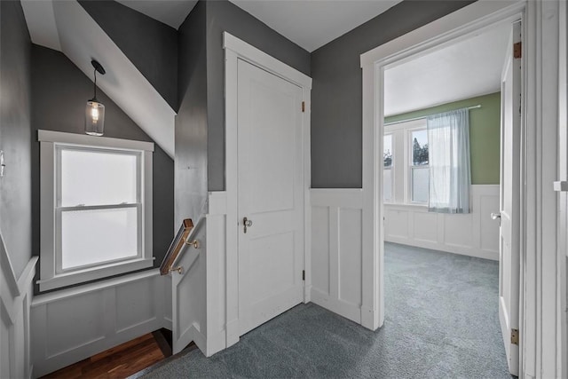 hallway with dark carpet and vaulted ceiling