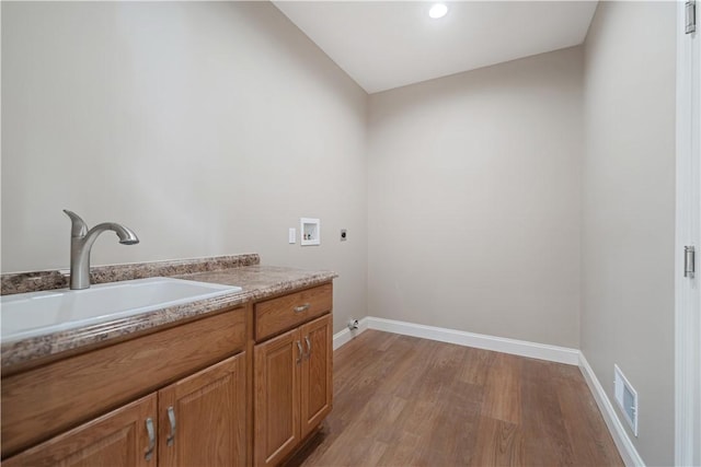 laundry room with light hardwood / wood-style floors, washer hookup, sink, hookup for an electric dryer, and cabinets