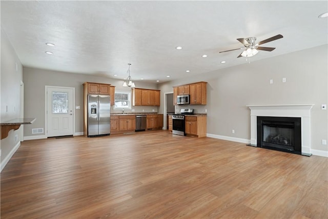 kitchen featuring decorative light fixtures, sink, light hardwood / wood-style flooring, and appliances with stainless steel finishes