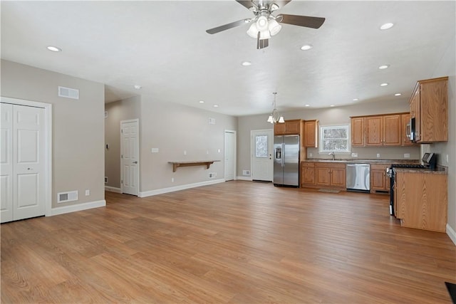 kitchen featuring ceiling fan, sink, decorative light fixtures, light wood-type flooring, and stainless steel appliances