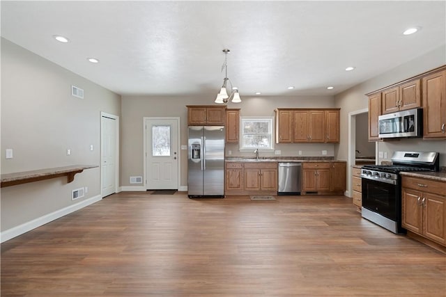 kitchen featuring decorative light fixtures, dark wood-type flooring, appliances with stainless steel finishes, and sink