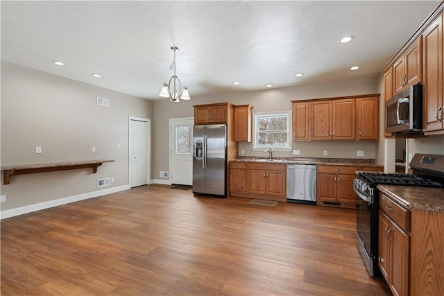 kitchen featuring sink, decorative light fixtures, appliances with stainless steel finishes, and dark wood-type flooring