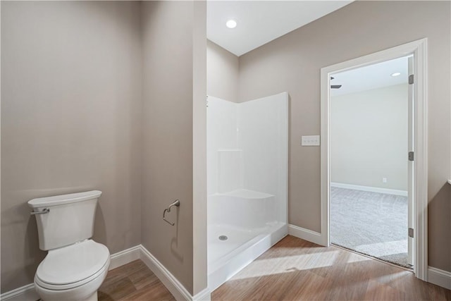 bathroom featuring wood-type flooring, toilet, and walk in shower