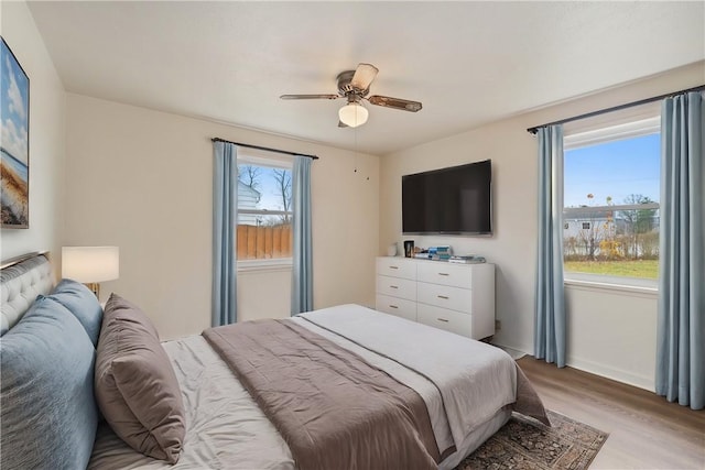 bedroom featuring light hardwood / wood-style floors, multiple windows, and ceiling fan